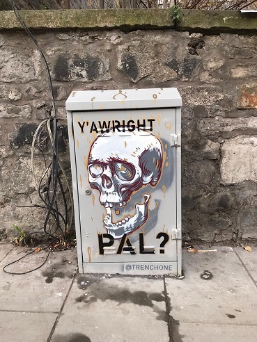 Mural painted by Trench One on a utility box which has a skull and the slogan Y’alright Pal? painted on it. 