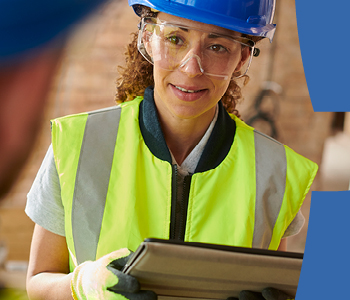 Woman with clipboard wearing high visibility jacket and hard hat.