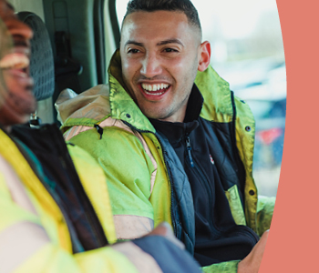 Two men a van wearing high visibility jackets.
