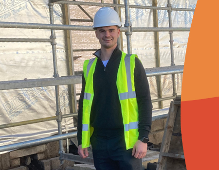 Man standing in a construction site with hard hat and high visibility vest.