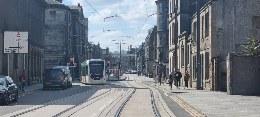 View of tram on Constitution Street with the Robert Burns statue in the background