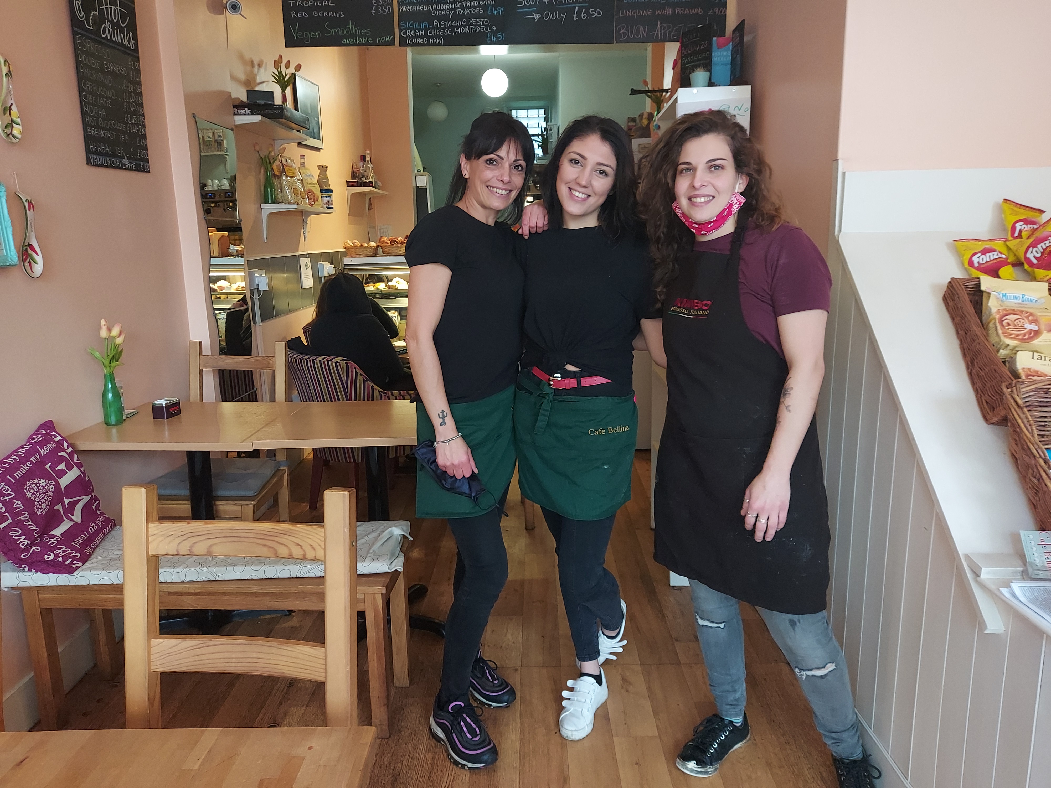 Three women standing inside Cafe Bellina.