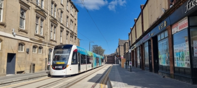 Tram on Foot of the Walk tram stop with businesses seen on the right