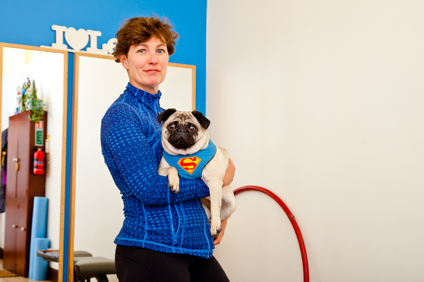 Business owner Tracey Griffen holding pet pug in her fi8tness studio.