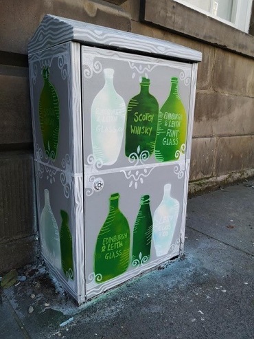 Mural with green bottles on a grey background on a utility box. 
